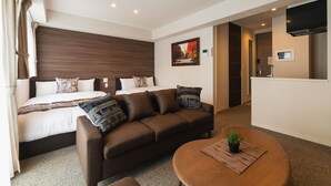 A modern hotel room with a bed, a brown sofa, a round coffee table, and a TV mounted on the wall. - GRAND BASE Mojiko (Kitakyushu)