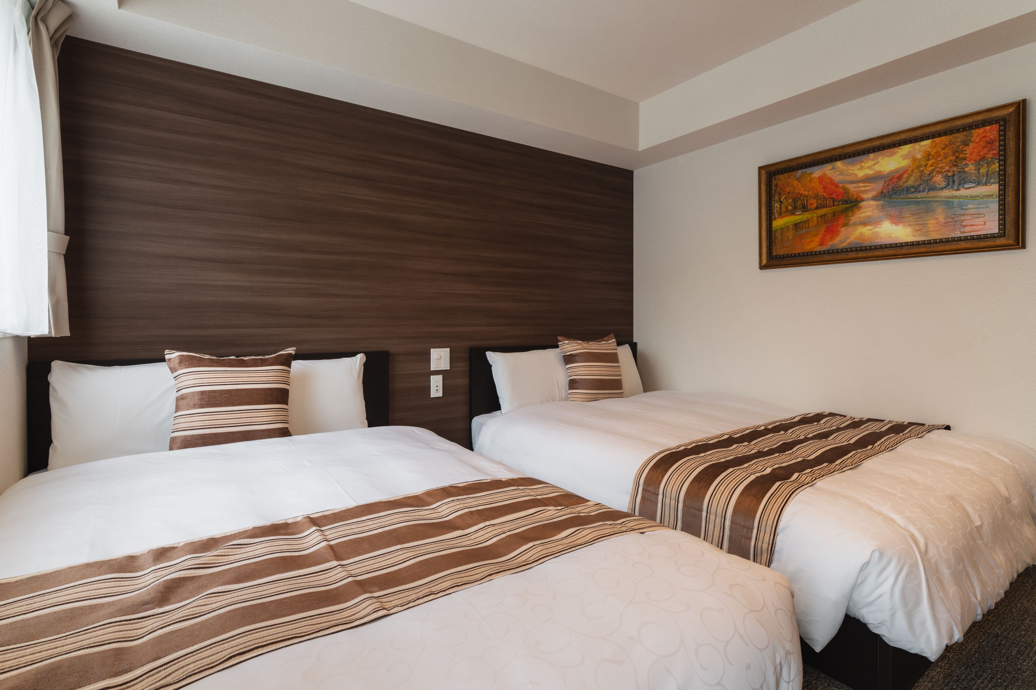 A hotel room with two beds, a wooden headboard, and a painting on the wall.