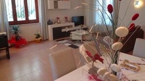 A modern living room with a dining area, a TV, and a plant. - B&B Eden di Segesta (Calatafimi)