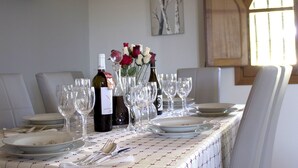 A dining table set with plates, glasses, and wine bottles, with a vase of flowers and a painting on the wall. - B&B Eden di Segesta (Calatafimi)