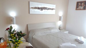 A hotel room with a bed, bedside tables, a lamp, a vase with flowers, and a painting on the wall. - B&B Eden di Segesta (Calatafimi)
