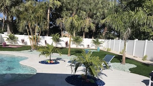 A swimming pool with lounge chairs and palm trees.