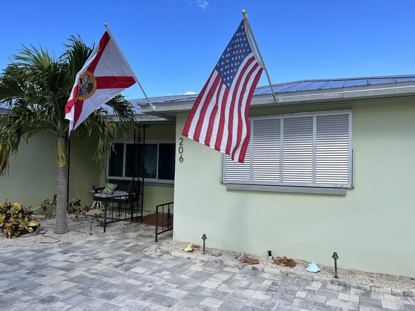 Une maison avec le numéro « 206 » sur le mur, un mât avec un drapeau et un palmier.