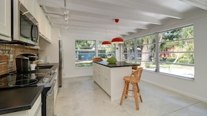 A modern kitchen with a large island, stainless steel appliances, and a view of the outdoors.