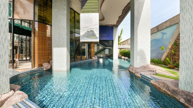 An indoor swimming pool with clear blue water, surrounded by tiled walls and pillars. - OYO 143 Dday Resotel Pattaya Hotel (Pattaya)