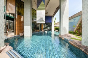 An indoor swimming pool with clear blue water, surrounded by tiled walls and pillars. - OYO 143 Dday Resotel Pattaya Hotel (Pattaya)