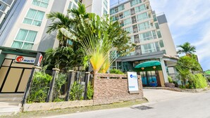 A modern hotel with a stone facade, a palm tree in the foreground, and a sign for 'd day' in the entrance. - OYO 143 Dday Resotel Pattaya Hotel (Pattaya)