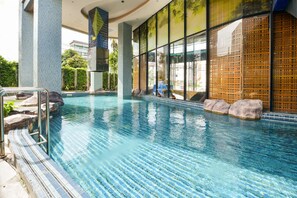 An indoor swimming pool with clear water, tiled steps, and a view of the outdoors through large windows. - OYO 143 Dday Resotel Pattaya Hotel (Pattaya)