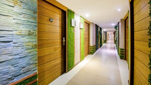 A hotel corridor with wooden paneling, stone wall accents, and green vertical gardens. - OYO 143 Dday Resotel Pattaya Hotel (Pattaya)