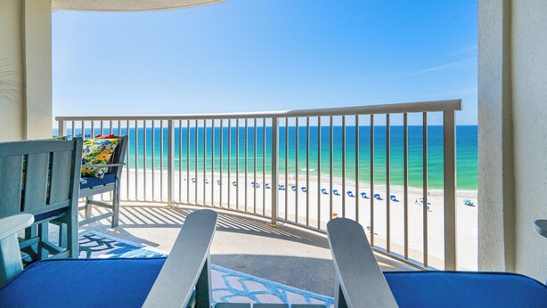 A balcony with a view of the beach, a chair, and a table. - Royal Palms 1BR 2BA! Condo 1007 ~ (Gulf Shores)