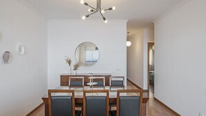 A modern dining area with a wooden table and chairs, a round mirror on the wall, and a chandelier.