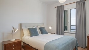 A bedroom with a bed, bedside tables, and a window with curtains.