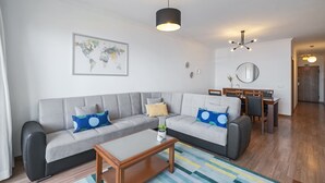 A modern living room with a grey sofa, wooden coffee table, and a world map on the wall.