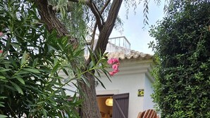 A stone wall with a white lamp, green plants, and wooden chairs in a garden area. - Arrábida Sea & Country side Villa (Azeitão)