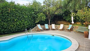 A swimming pool with a stone border, surrounded by a hedge, and six lounge chairs with umbrellas. - Arrábida Sea & Country side Villa (Azeitão)
