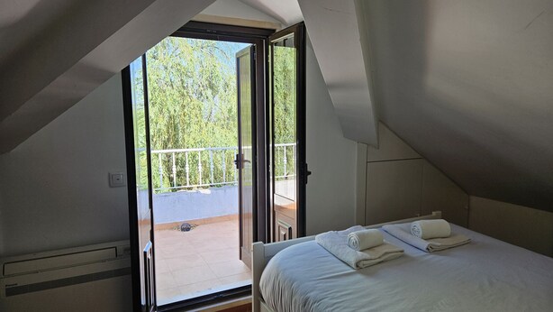 A bedroom with a bed, two towels, and a balcony with a railing. - Arrábida Sea & Country side Villa (Azeitão)