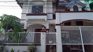 Un edificio de varios pisos con fachada blanca, detalles en rojo y un acceso con portón.