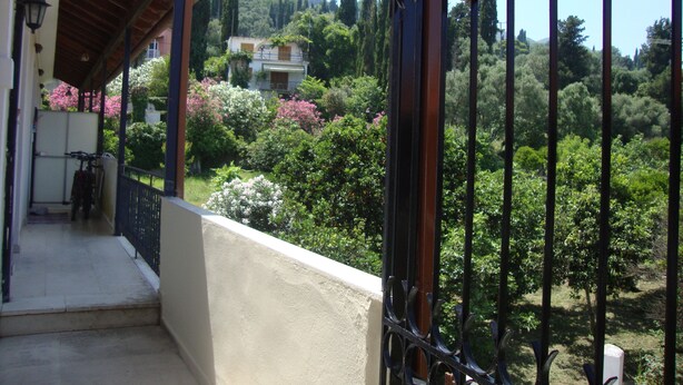 A gated entrance to Demirene Studios with a view of a lush garden and a hillside in the background. - Anya Studios (Corfu)