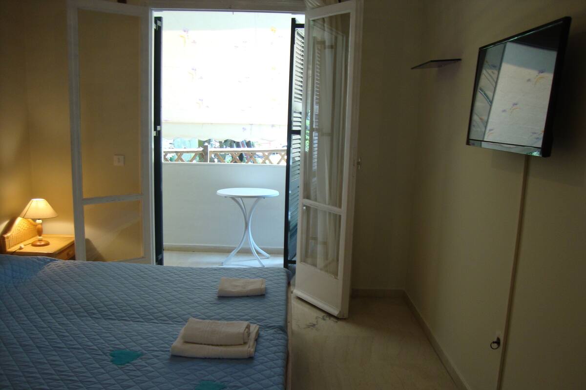Une chambre d’hôtel avec un lit, une lampe de chevet, une petite table et un balcon avec vue.