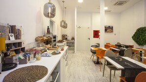 A modern dining area with white walls, a long counter with food items, and multiple tables with chairs. - Casual Socarrat Valencia Hotel by Casual Hoteles (Valencia)