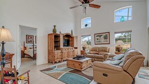 A spacious living room with a ceiling fan, a large wooden cabinet, a leather sofa, and a dining area with a lamp. - EV_234 - 4 Bed 2 Bath House with Games Room and Access to Resort Amenities (Davenport)