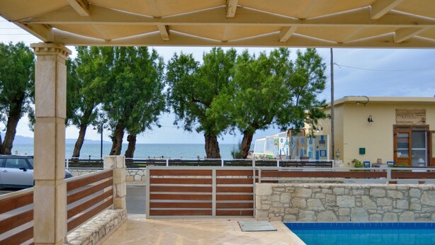 A covered outdoor area with a swimming pool, stone walls, and a view of the sea. - Nopigia Mare Villa (Kissamos)