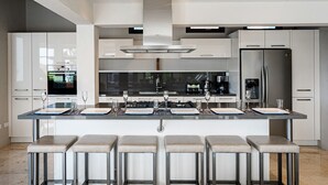 A modern kitchen with a central island, stainless steel appliances, and bar stools. - STUNNING Villa w/Infinity Pool& Outdoor Kitchen! Across from Marriott! (Noord)
