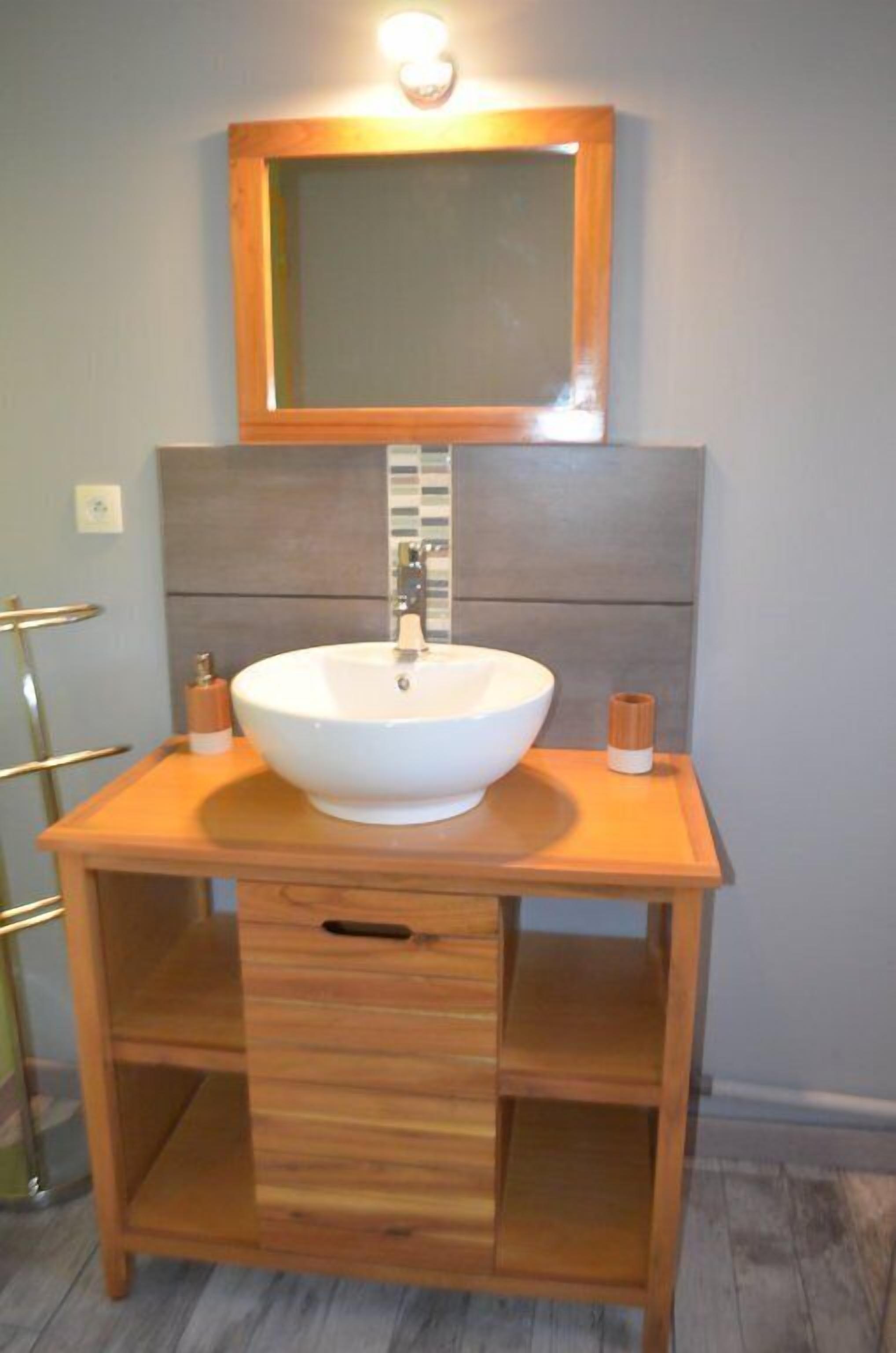 A bathroom with a wooden vanity, a white sink, and a mirror above it.