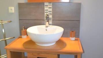 A bathroom with a wooden vanity, a white sink, and a mirror above it.