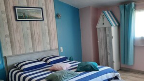 A bedroom with a bed, two stools, a dresser, and a wall-mounted picture. - Chambres d'hotes L'Amandier (Maury)