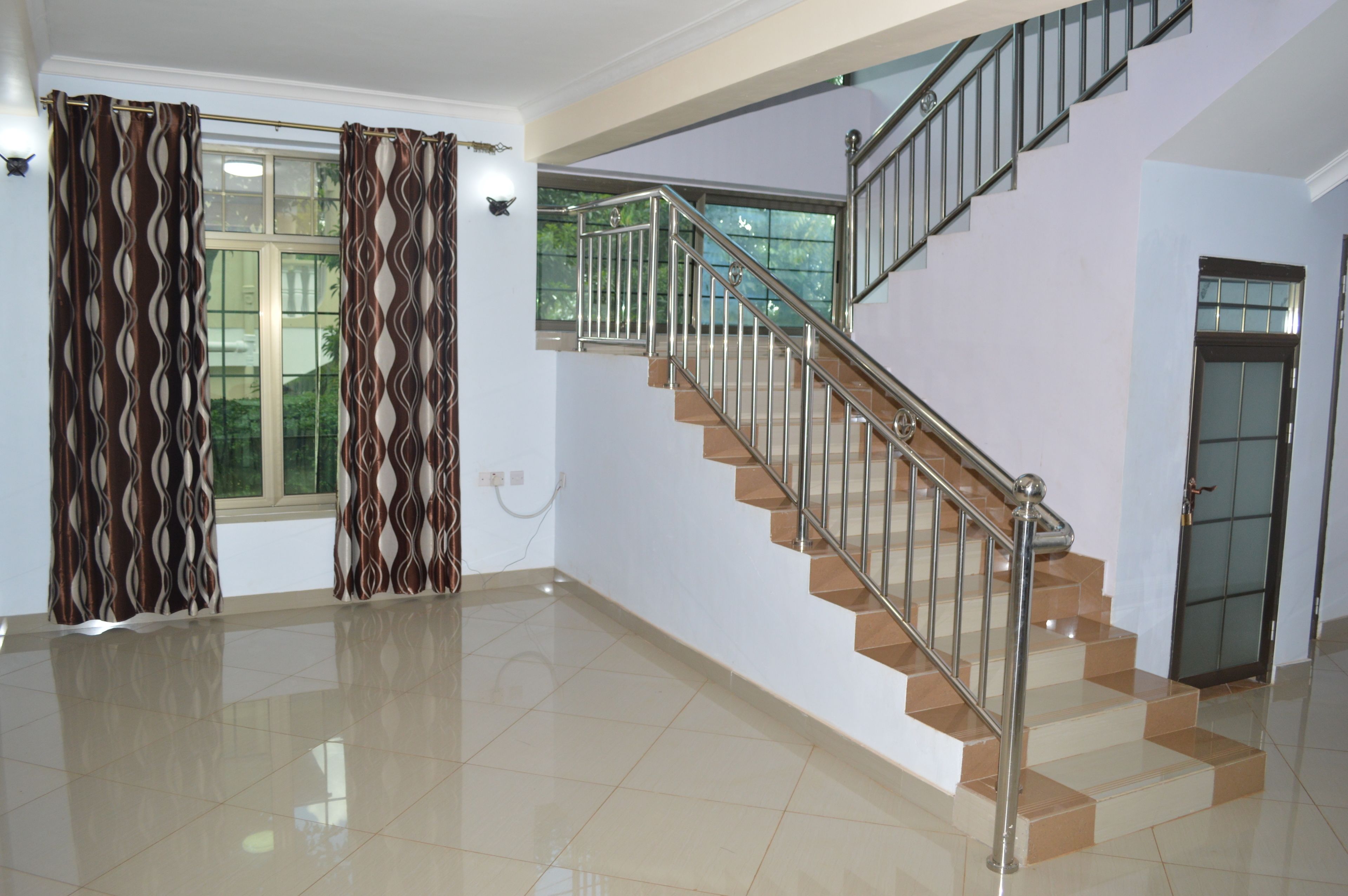 A spacious room with a staircase, a large window, and a door.