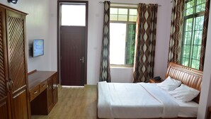 Ein Schlafzimmer mit einem Holzbett, einem Kleiderschrank, einem Schreibtisch und einem Fenster mit Vorhängen.