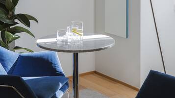 A modern room with a round table, two blue chairs, a floor lamp, and a large mirror on the wall.