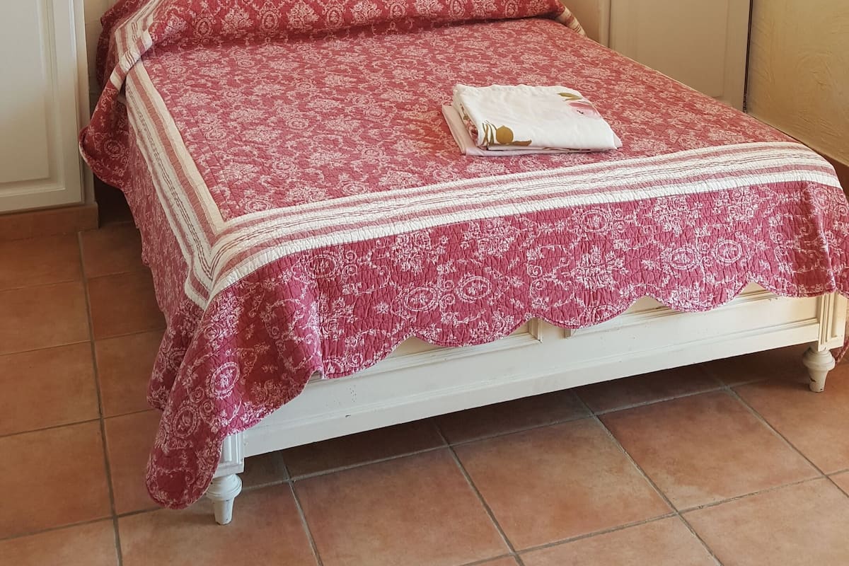Une chambre à coucher avec un lit, un lustre, un tableau encadré et une porte.