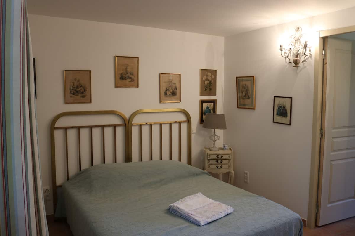 Une chambre à coucher avec un lit, une table de chevet et une lampe fixée au mur.