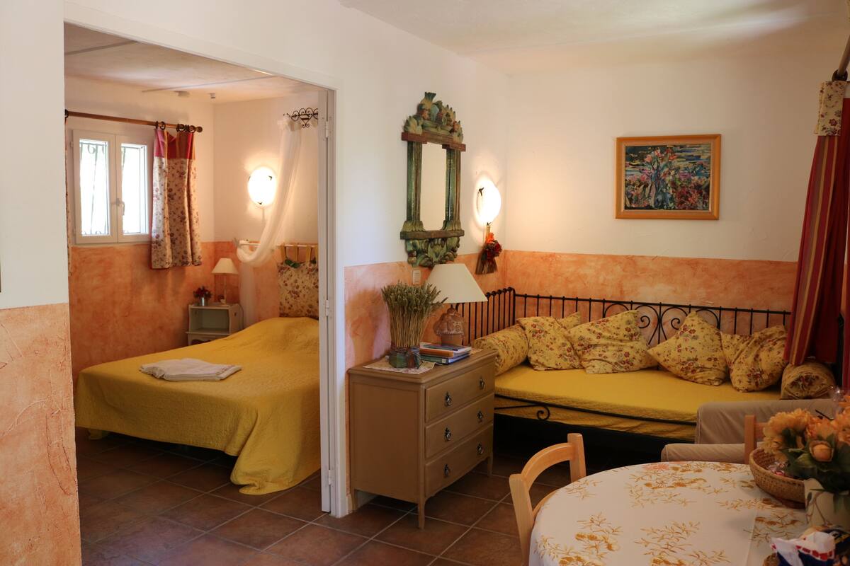 Une chambre avec deux lits, une table de chevet, une commode, un miroir et un tableau au mur.