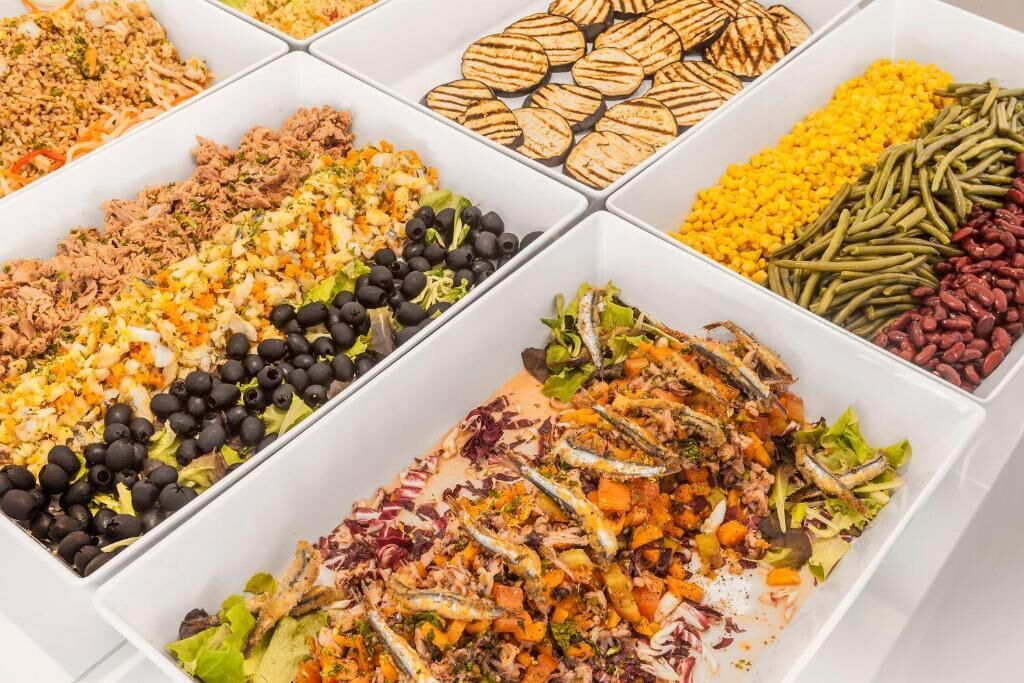 A buffet with various food options including grilled vegetables, salads, and different types of beans.