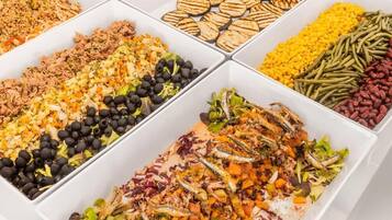 A buffet with various food options including grilled vegetables, salads, and different types of beans.