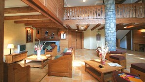 A spacious lobby with wooden furniture, a stone pillar, and a fireplace.