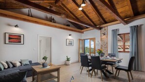A cozy living room with a wooden ceiling, a dining table set for four, and a sofa. - Beautiful 3-BR villa with pool and sea view just above Rogoznica (Rogoznica)
