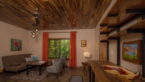 A modern living room with a wooden ceiling, a sofa, a coffee table, a dining table, and a view of the outdoors through large windows. - Avatar Eco Residence (Puerto Jiménez)