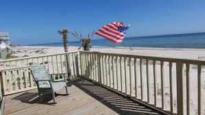 A wooden deck with a railing, a bench, and a flag.
