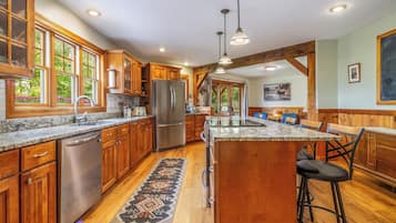 A spacious kitchen with wooden cabinets, stainless steel appliances, and a large island with bar stools.