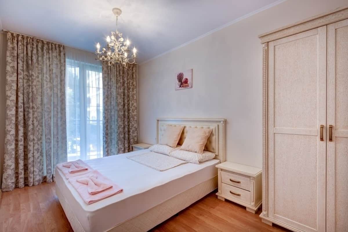 A bedroom with a large bed, a nightstand, a wardrobe, and a chandelier.