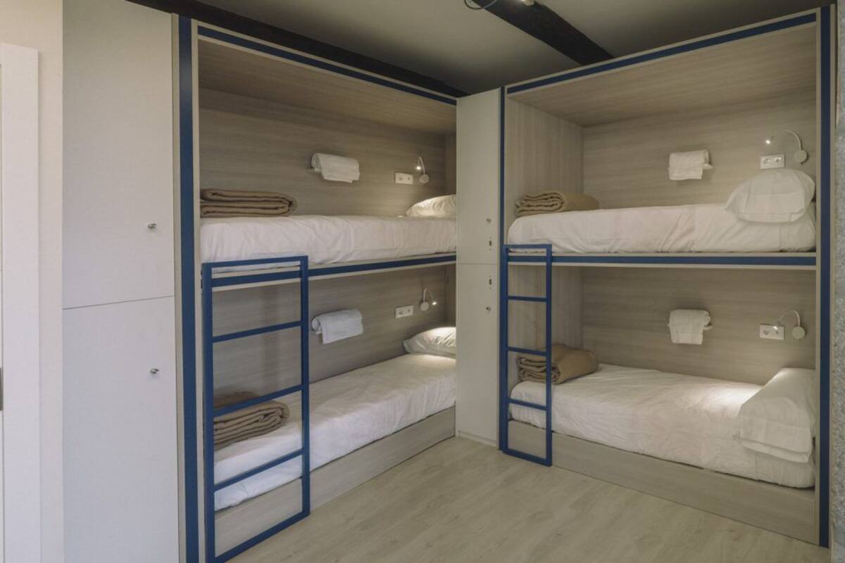 Ein Zimmer mit Etagenbetten, jeweils mit einer Leiter, und einem weißen Kleiderschrank.
