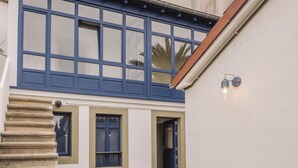 Un bâtiment doté d’une fenêtre à cadre bleu, d’un escalier en pierre et d’un luminaire fixé au mur.