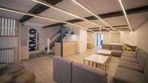 Un hall d’hôtel moderne avec un escalier, des espaces de détente et un comptoir d’accueil.