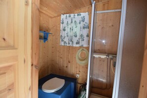 A wooden cabin bathroom with a toilet, shower, and a curtain. - Solferie Hytte nær Dyreparken (Kristiansand)