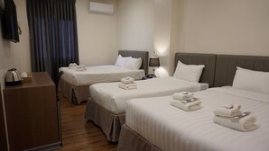 A hotel room with two beds, a desk, a lamp, and a window with curtains. - Crevice Hotel (Davao)
