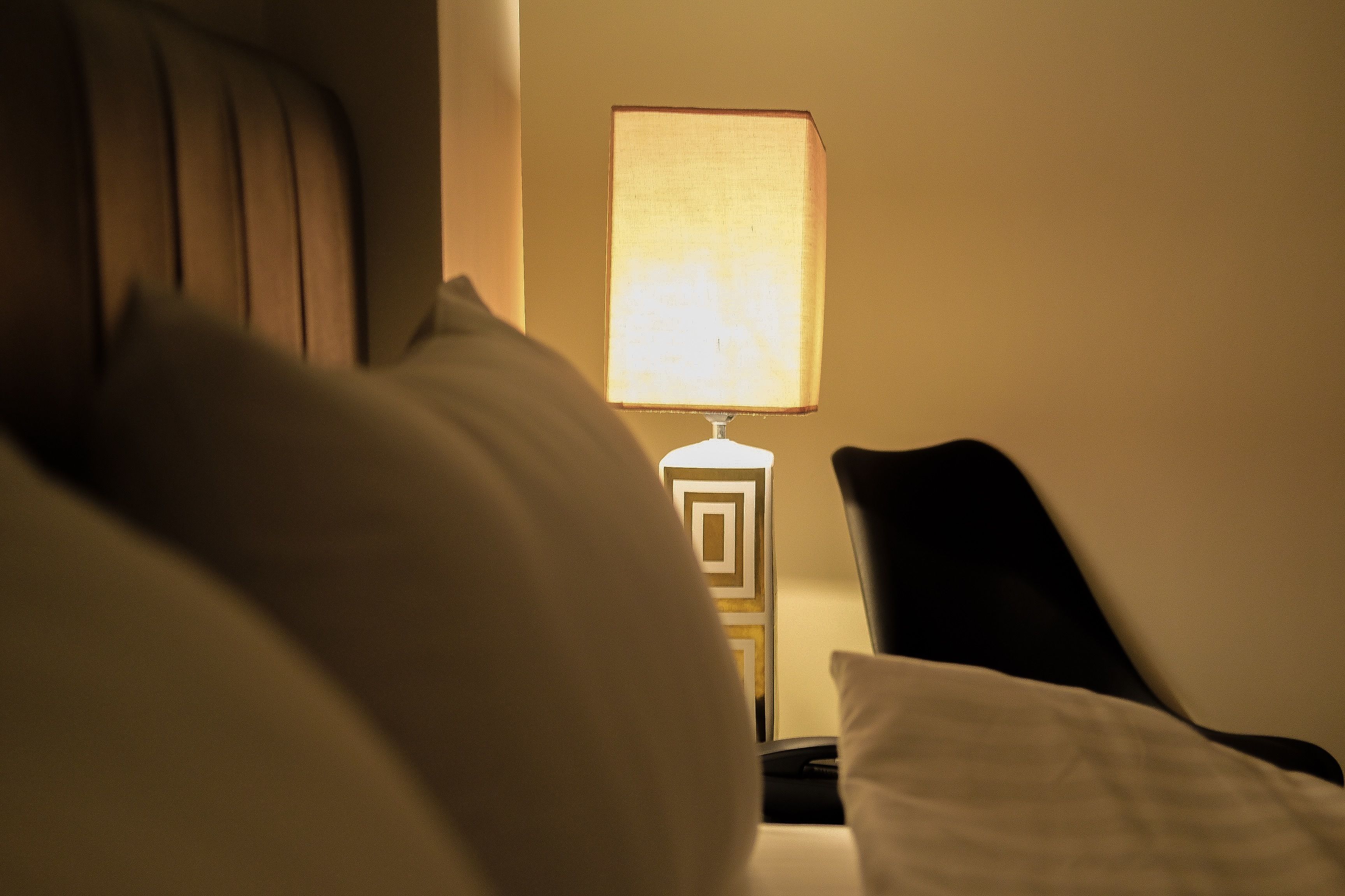 Una cama con almohadas y una lámpara de noche en una habitación de hotel.